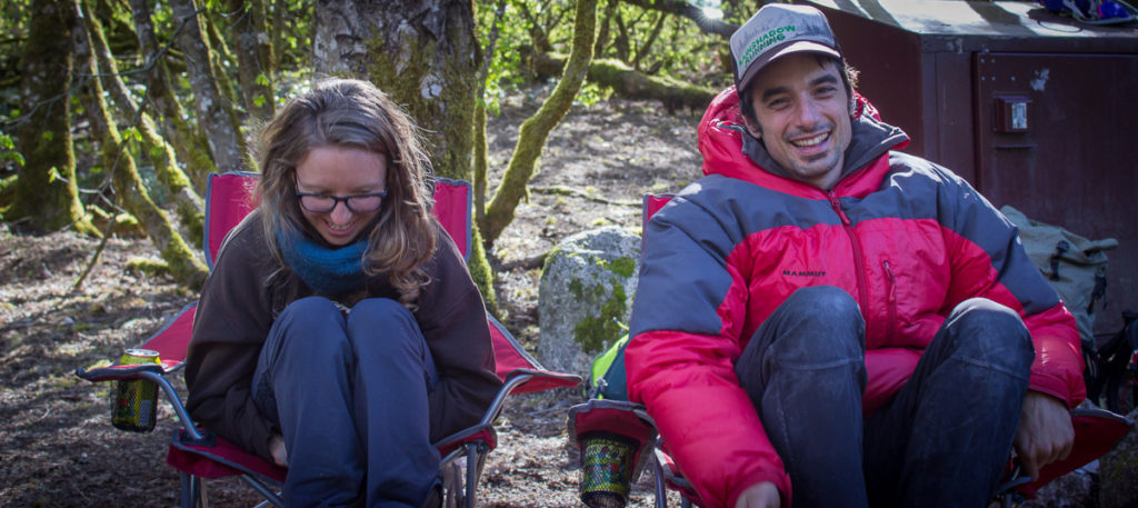 A woman and a man laughing while sitting in camp chairs.