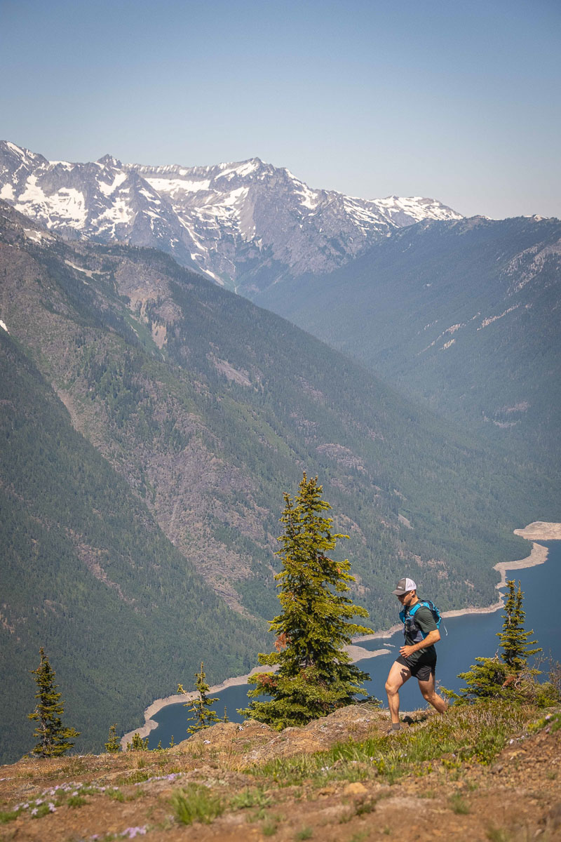 A man trail running in front of Ross Lake in the North Cascades
