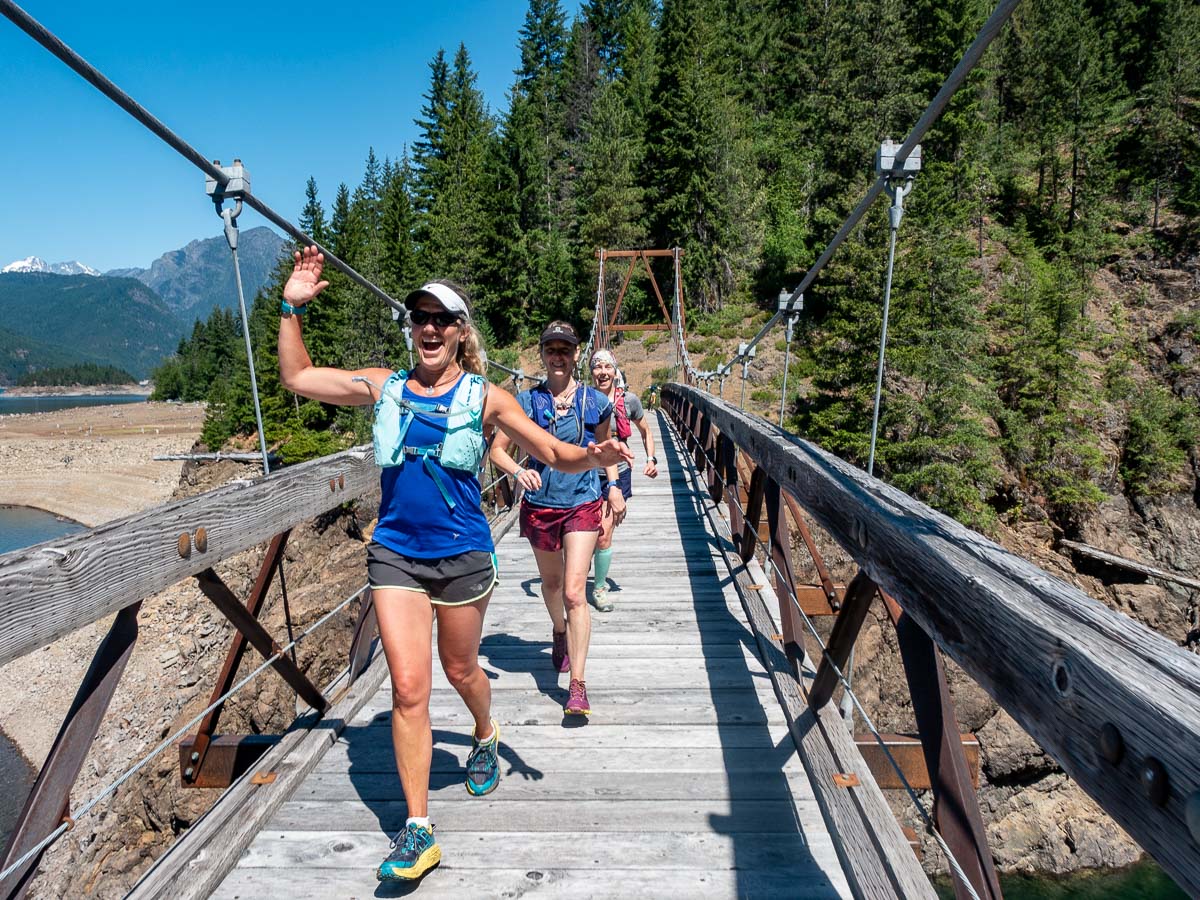 trail runners cross a suspension bridge