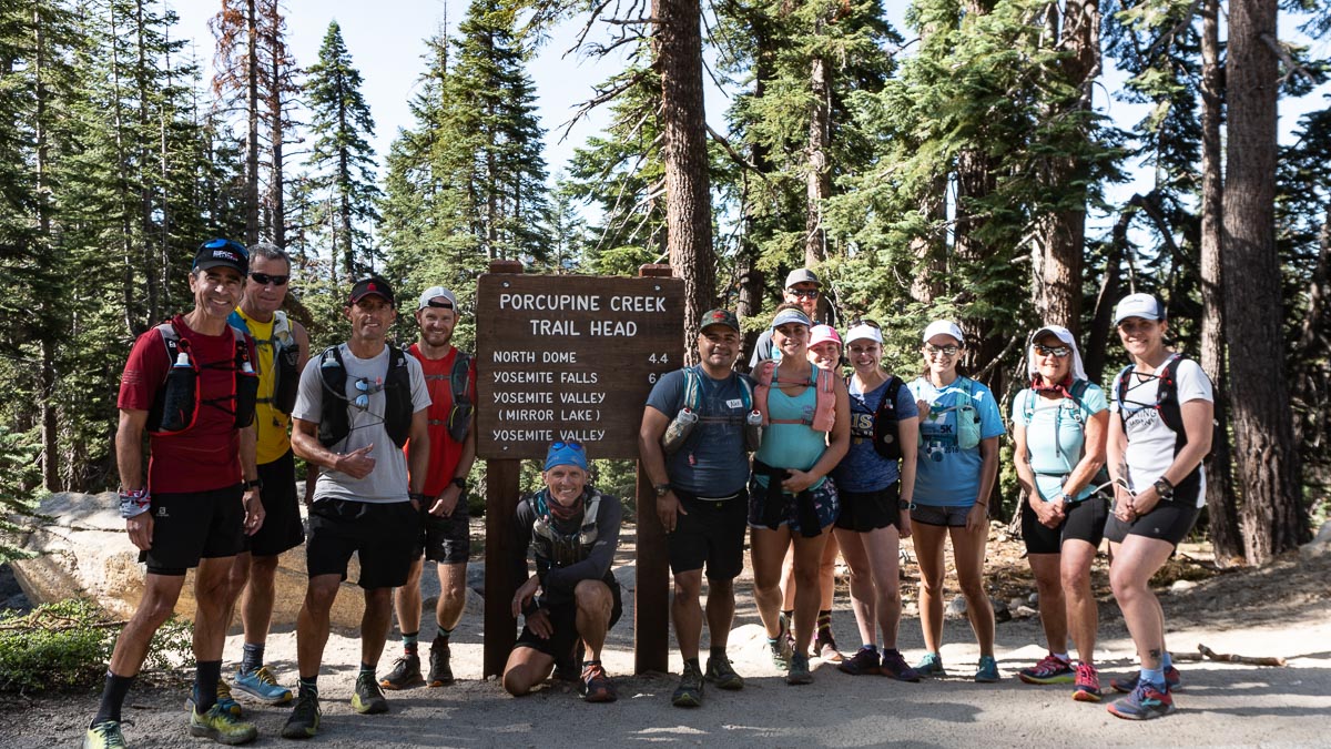 a group of happy runners in front of a trial sign.