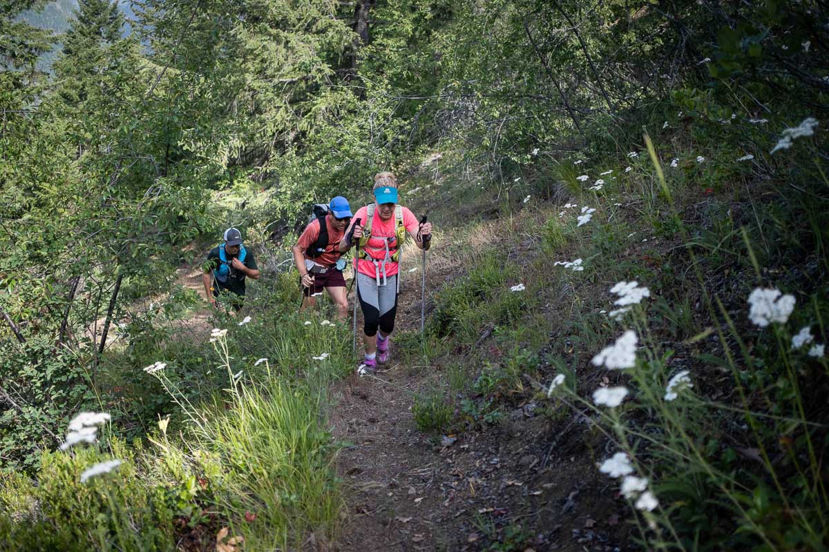 three trail runners climb a steep trail